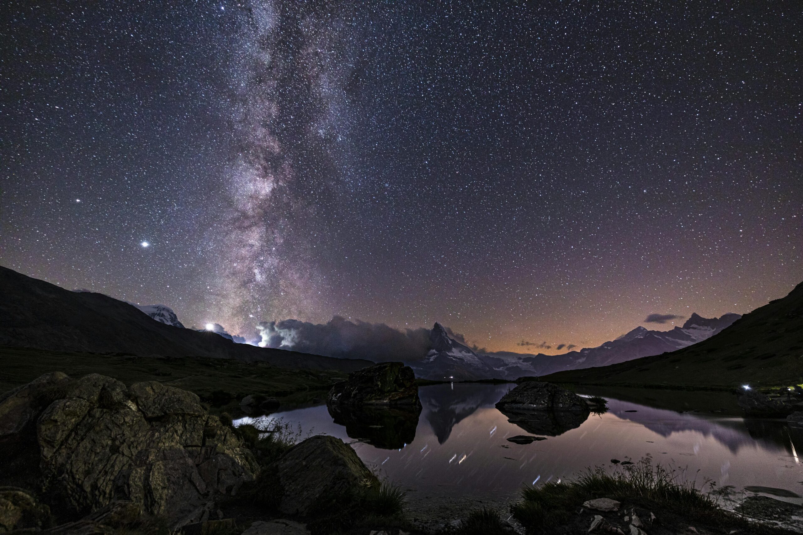 A breathtaking view of the Milky Way over Stellisee Lake, Zermatt, reflecting the night sky and mountains.